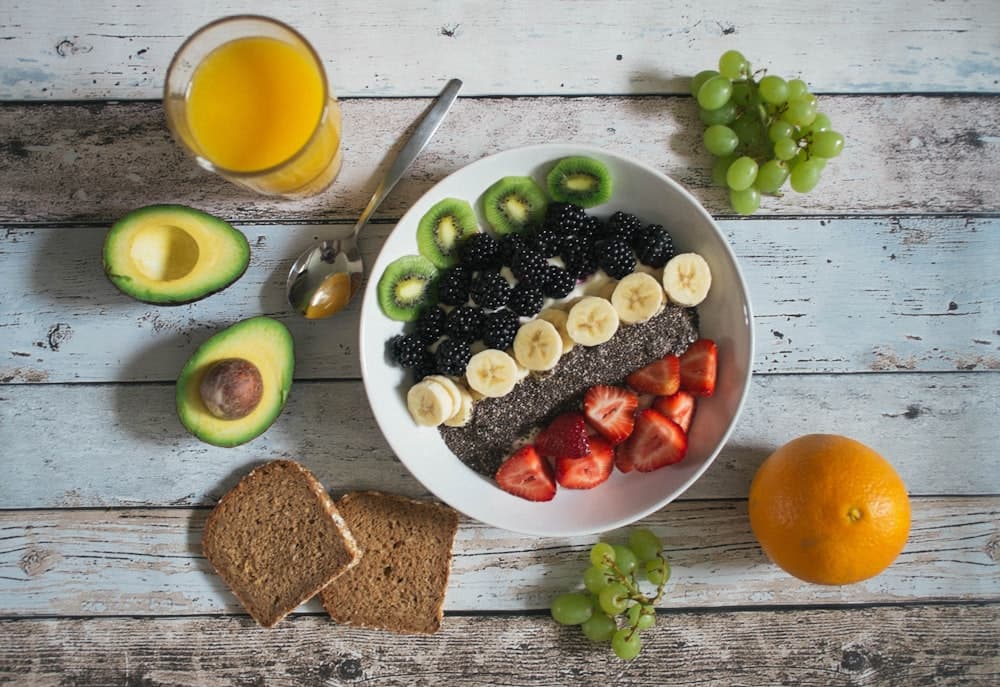 Bol d'esmorzar amb fruita fresca i llavors sobre fusta