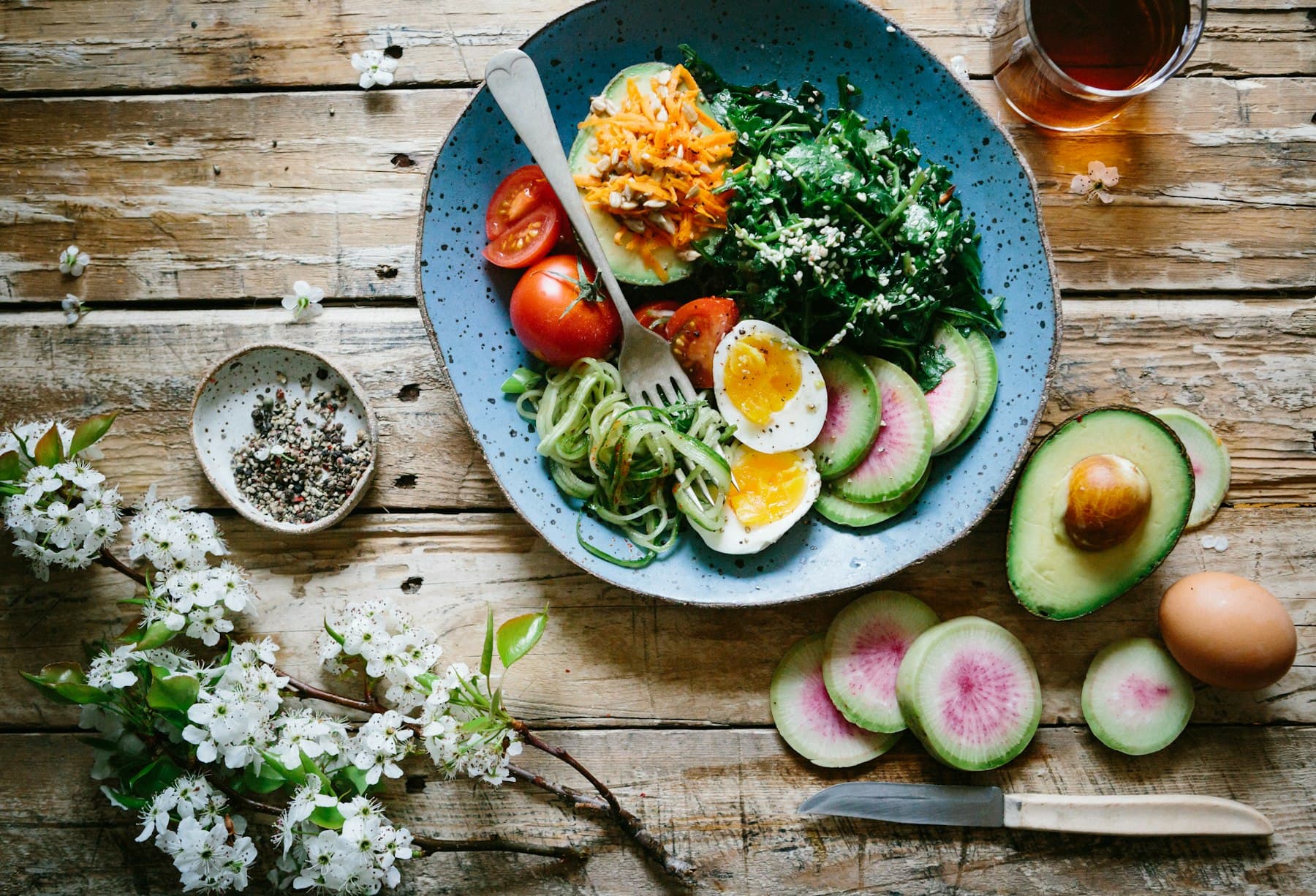 Plat saludable amb vegetals frescos, ou i alvocat sobre fusta natural
